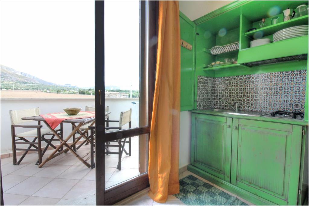 a kitchen with green cabinets and a table with a window at Senia in San Vito lo Capo