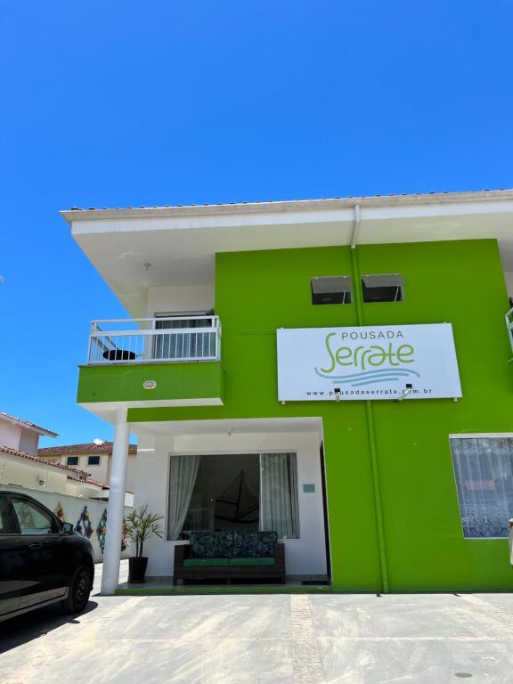 een groen gebouw met een bord erop bij Pousada Serrate in Ubatuba