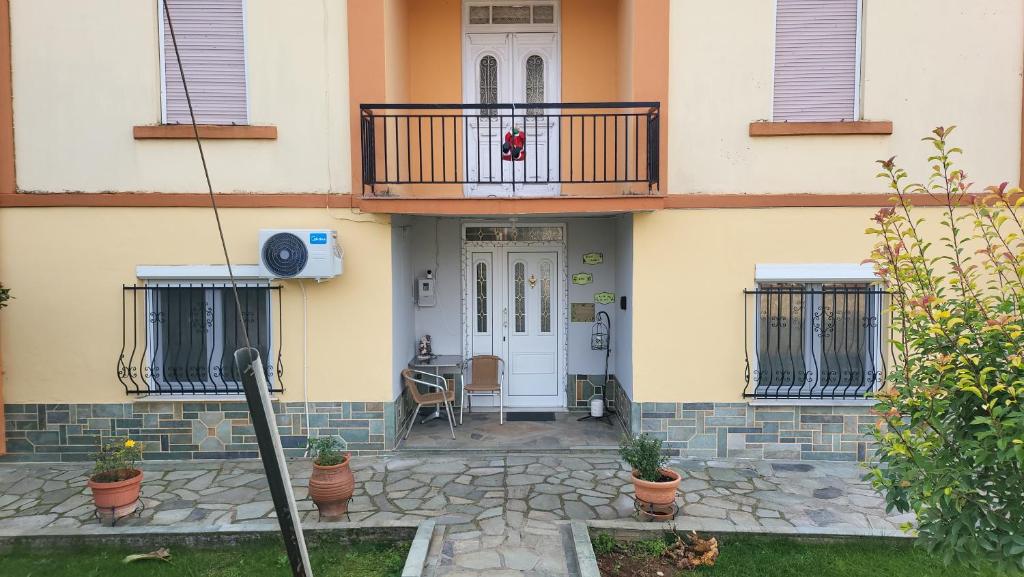 een gebouw met een deur en een balkon met planten bij Αυλή της Ελιάς in Prosotsáni