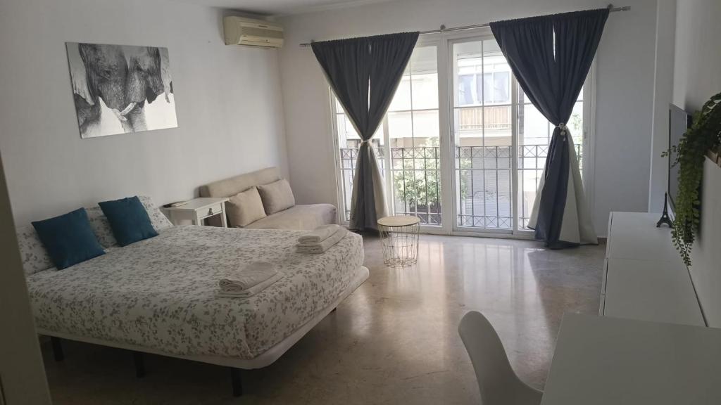 een slaapkamer met een bed, een bank en ramen bij Alojamiento Bruckner in Málaga