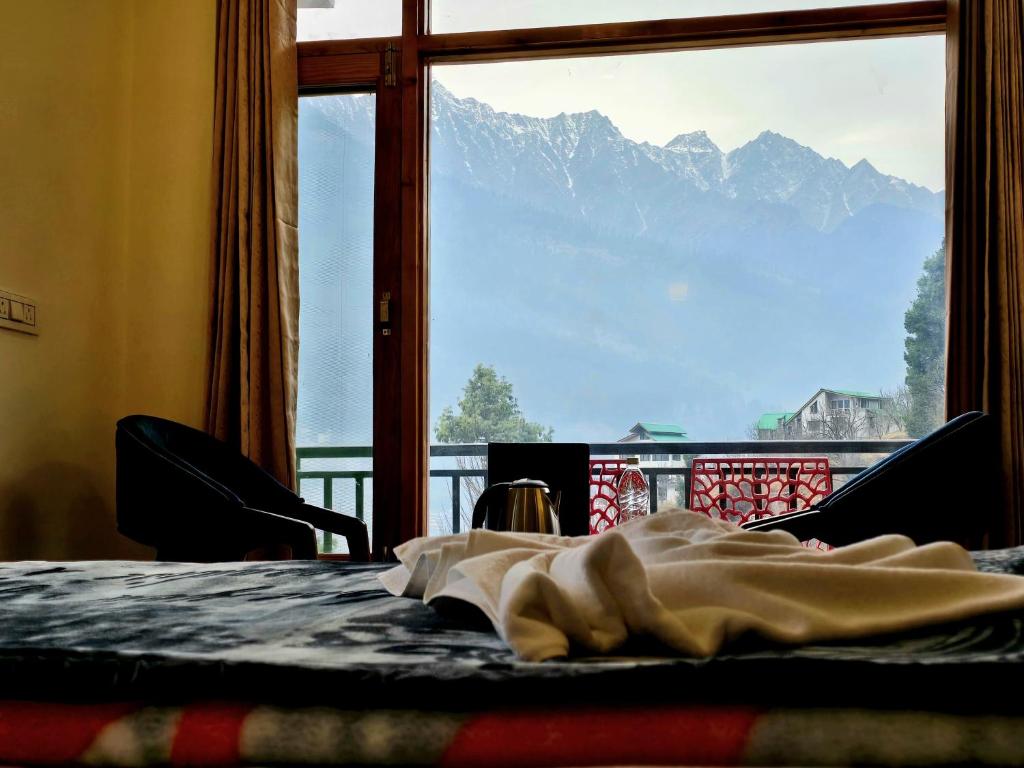 een kamer met een groot raam met uitzicht op een berg bij North Star Homestay Manali in Bashist