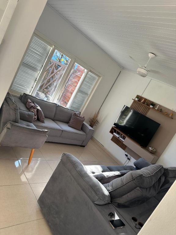 a living room with a couch and a tv at Conforto a 100 m do mar in Tramandaí