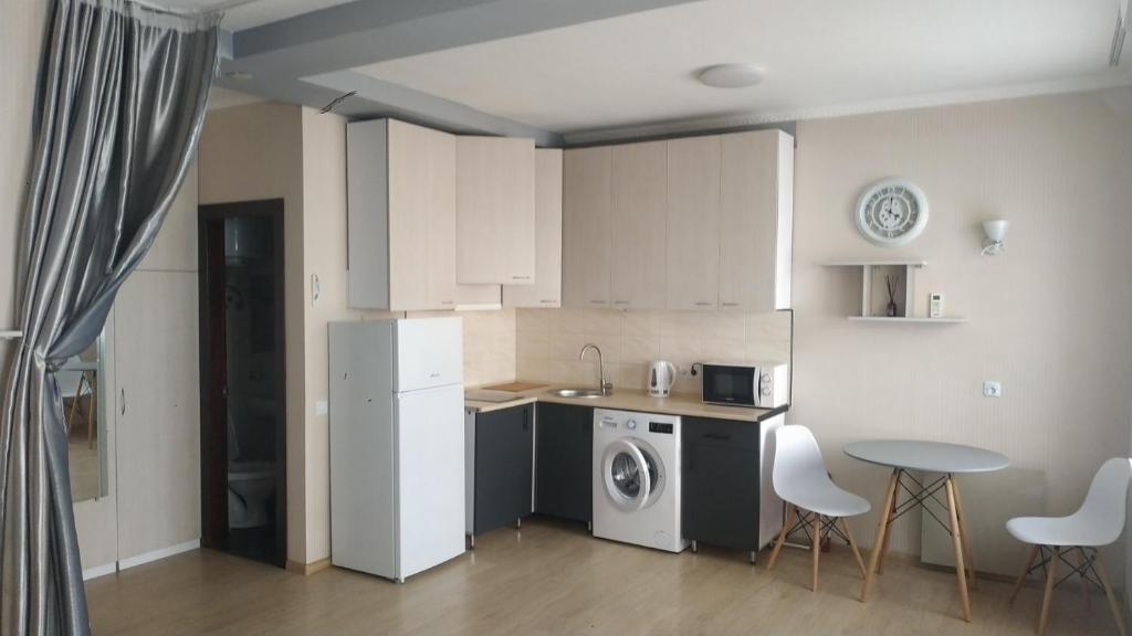 a kitchen with a refrigerator and a table and a dishwasher at Современная студия-люкс, слобожанській in Samarovka