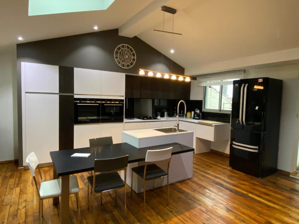 eine Küche mit einem schwarzen Kühlschrank sowie einem Tisch und Stühlen in der Unterkunft Le Savoyard in Saint Etienne