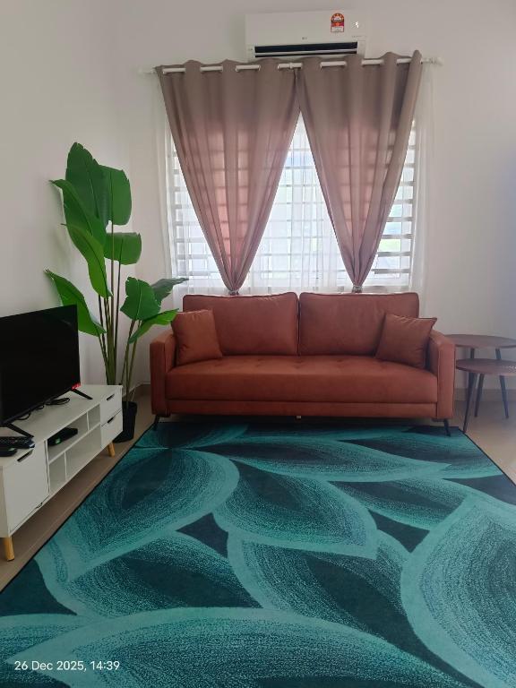a living room with a red couch and a green rug at Halia Homestay in Batu Pahat