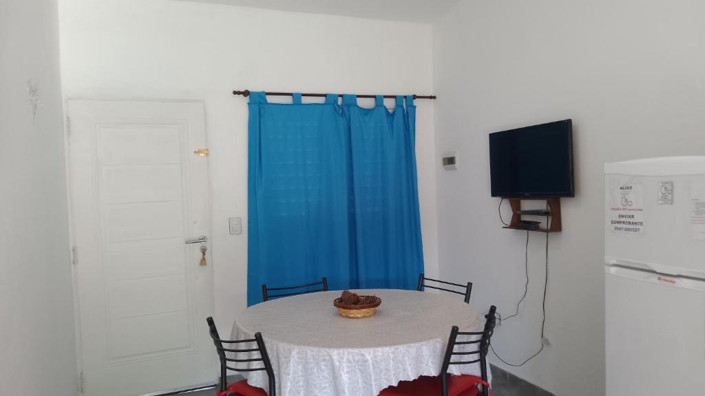 ein Zimmer mit einem Tisch, einem blauen Vorhang und einem Fernseher in der Unterkunft Departamento CR in Alta Gracia