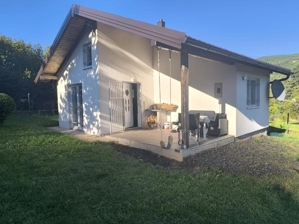 a house with a porch with a dog sitting on a deck at Vikendica Zeleni san in SJJ