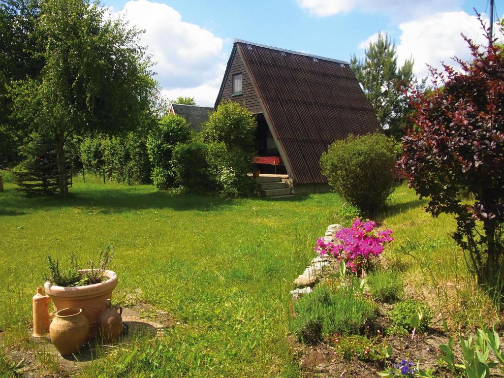 ein Hof mit einem Haus und ein paar Blumen im Gras in der Unterkunft Finnhütten Waldesruh in Lochow