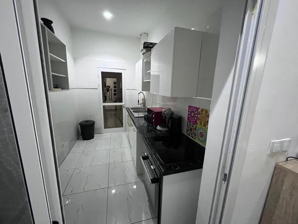 een keuken met witte kasten en een zwart aanrechtblad bij Terranga in Mbour