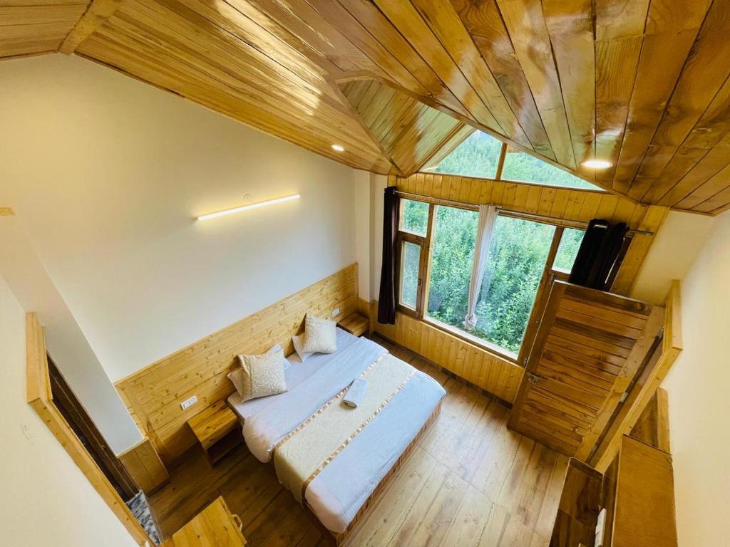a room with a bed and a large window at The Himalayan Castle View Retreat in Nagar