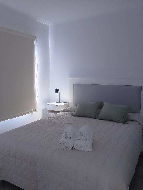 - une chambre blanche avec 2 serviettes sur un lit dans l'établissement El Estudio Céntrico con cochera, à Lobos