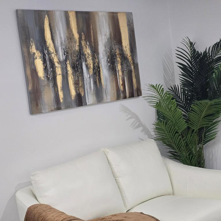 een witte bank in een woonkamer met een schilderij bij Ici Chez Vous in Trois-Rivières