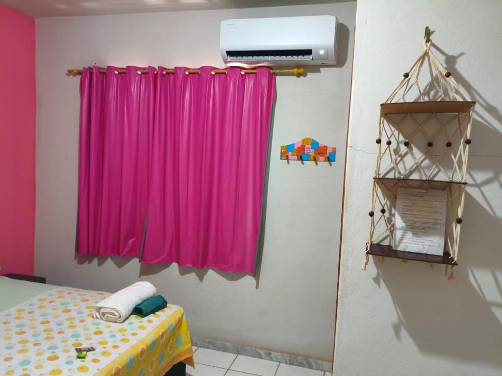 een kamer met een roze gordijn en een tafel bij Aquarela Suítes in Piúma