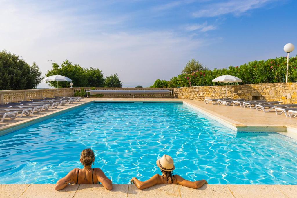 two people sitting in a swimming pool at Village de gîtes La Fontinelle in Bessas