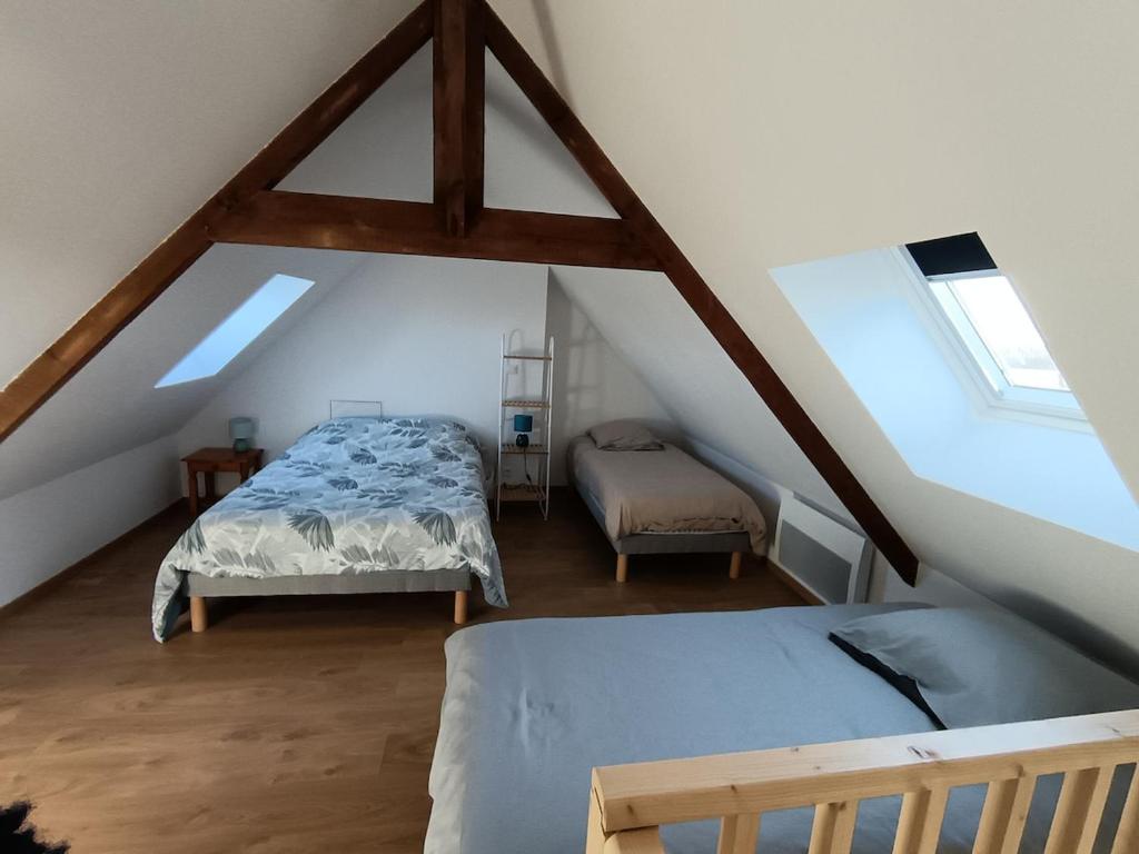 een slaapkamer op zolder met 2 bedden en 2 ramen bij Maison Les Hemmes d'Oye in Oye-Plage