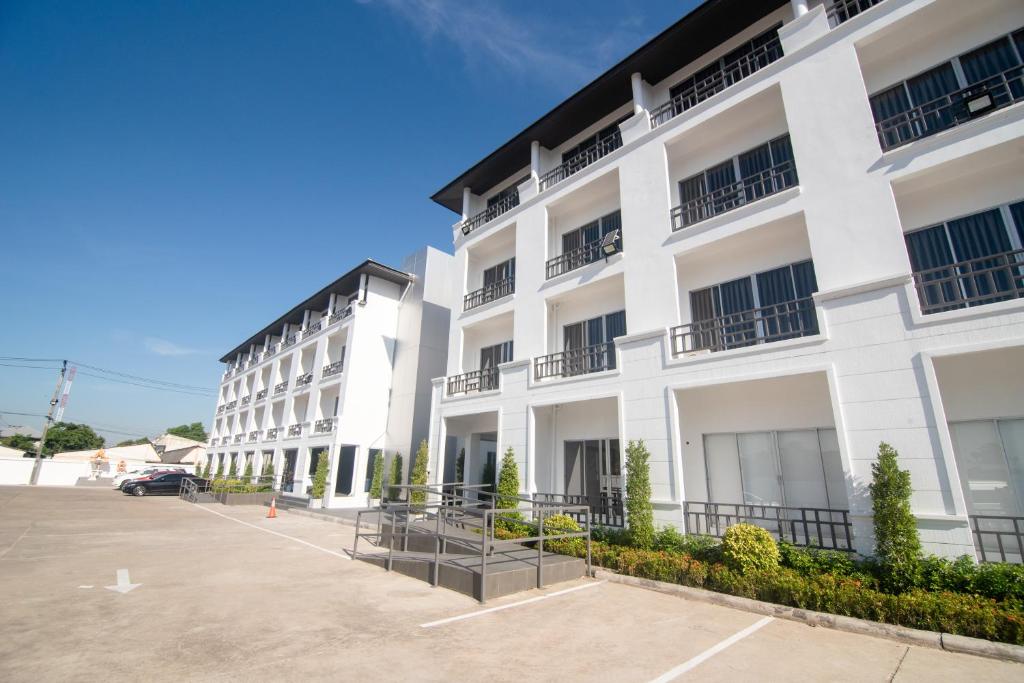 ein weißes Gebäude mit einem Parkplatz davor in der Unterkunft IU Hotel Donmueang Airport in Ban Don Muang
