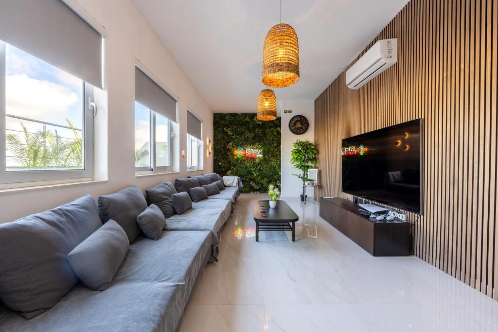 un soggiorno con un grande divano e una TV a schermo piatto di Design Luxury Penthouse with Private Pool a Żurrieq