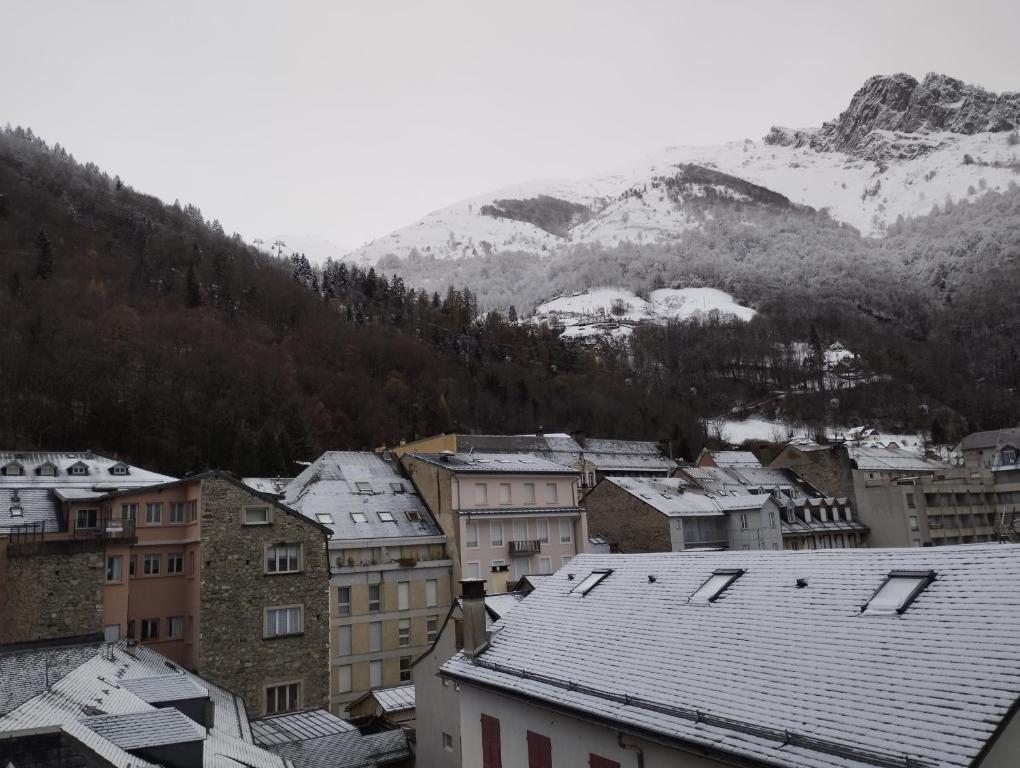 eine Stadt mit schneebedeckten Dächern und Bergen im Hintergrund in der Unterkunft appartement cosy hyper centre de Cauterets in Cauterets