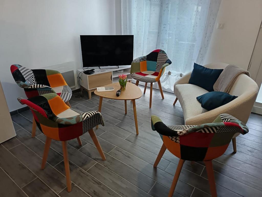 een woonkamer met diverse stoelen en een tv bij Maison La Tour Penchée in Oye-Plage