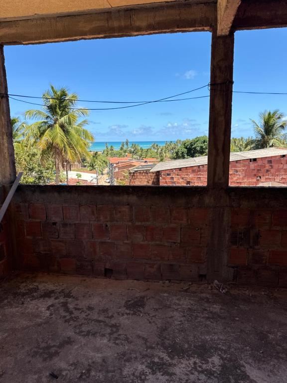 een lege kamer met een bakstenen muur en een groot raam bij Casa Praia Japaratinga in Japaratinga