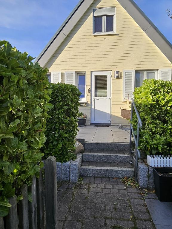 a yellow house with a white door and stairs at Zum Leuchtturm in Heiligenhafen