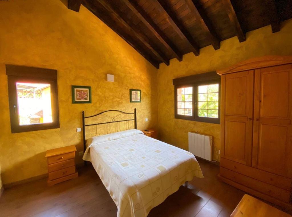 ein Schlafzimmer mit einem Bett und zwei Fenstern in der Unterkunft Los Avellanos Casa 2 in Celis