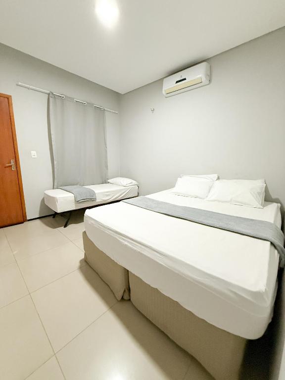 a white room with a bed and a chair at Pousada Cidade Nova in Campo Maior
