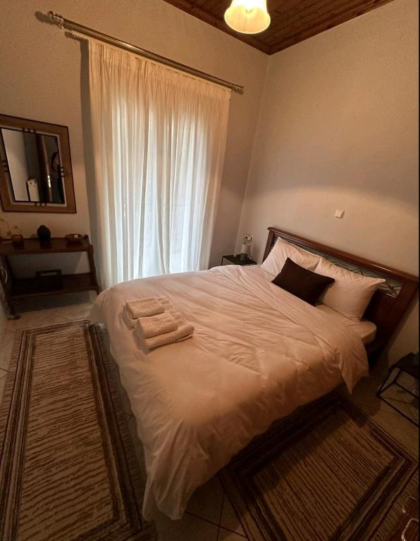 een slaapkamer met een bed met witte lakens en een raam bij House by the Mountain in Konitsa