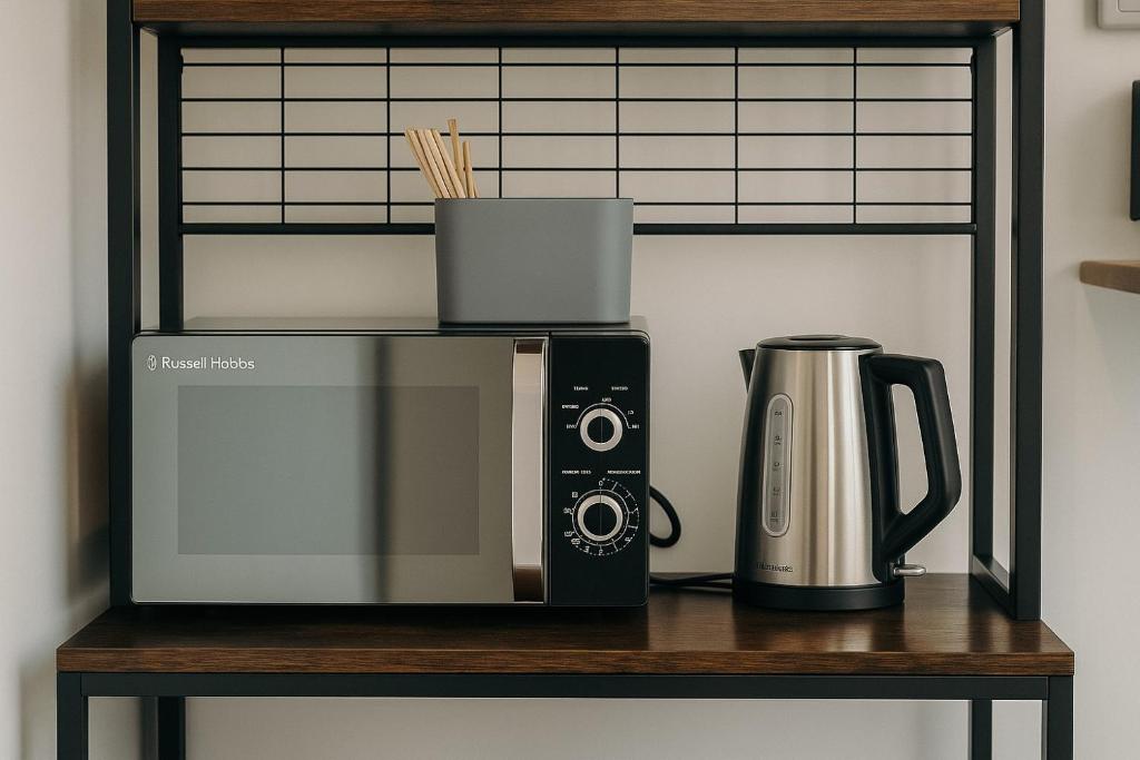 een magnetron en een koffiezetapparaat op een plank bij The GreenHouse Capsules in Londen