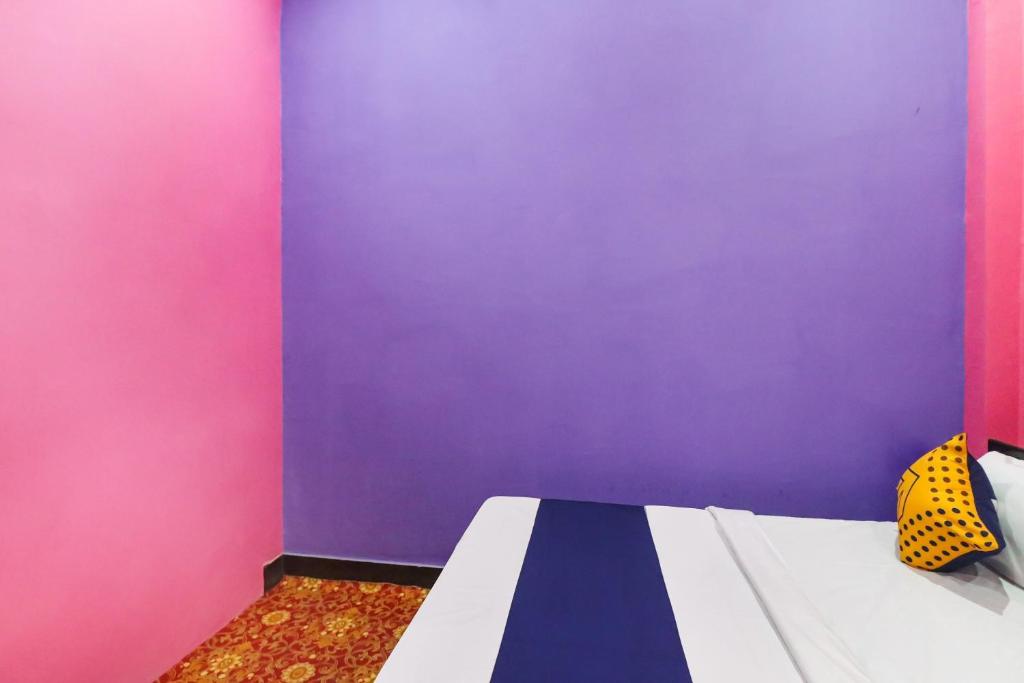 ein Schlafzimmer mit lila und rosa Wänden und einem Bett in der Unterkunft Hotel O Rajdhani Hotel in Kākori