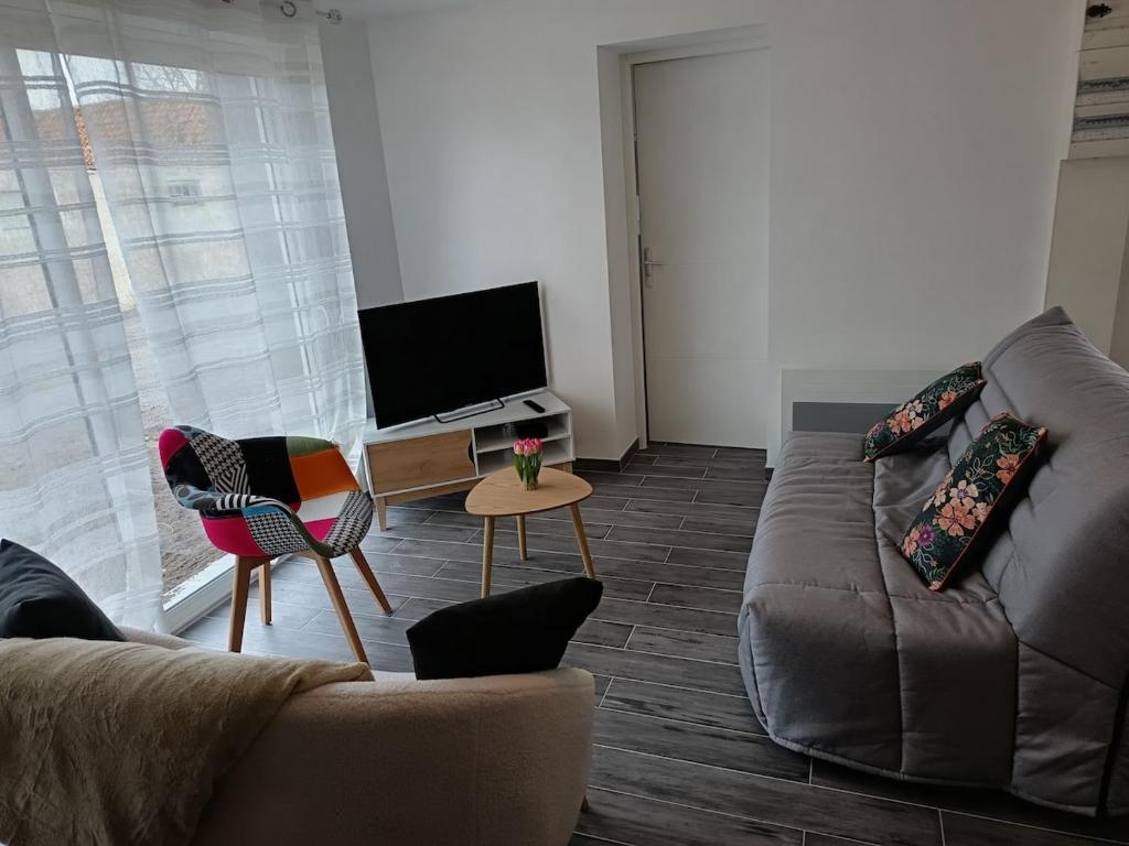 een woonkamer met een bank en een tv bij Maison Les Escardines in Oye-Plage
