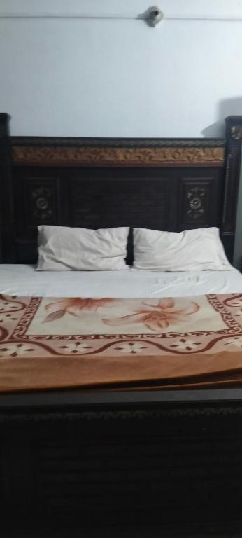 a bed with a wooden head board and white pillows at Hamala Inn Hotel in Abbottabad