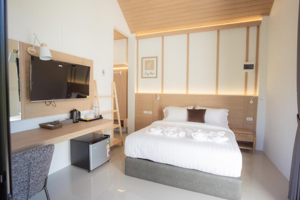 een slaapkamer met een bed, een bureau en een televisie bij Annrin cafe & Resort in Ban Song Phi Nong