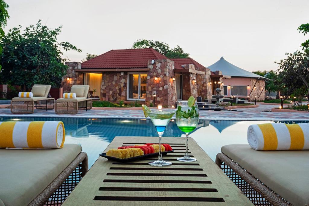 een tafel met glazen wijn naast een zwembad bij Wild Forest Sasan Gir Wildlife sanctuary in Sasan Gir