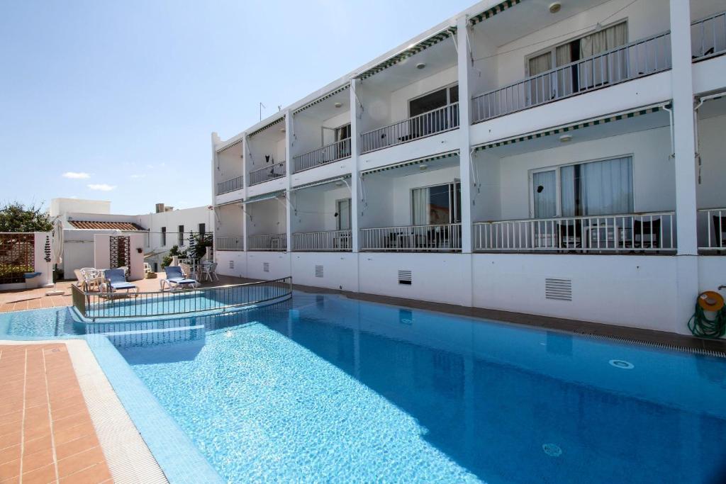 a hotel with a swimming pool in front of a building at Hostal S'Algaret in Fornells
