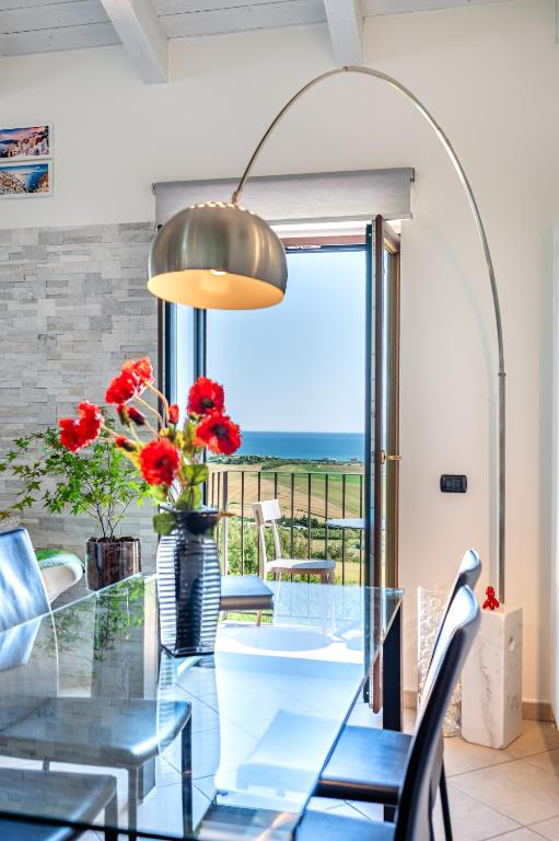 a dining room with a glass table with red flowers at Live Your Dream in San Costanzo