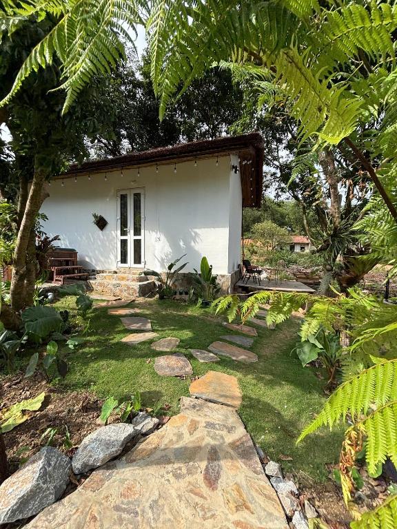 a garden with a small white house and trees at Chậm Viên Le Jardin in Thanh Lâm
