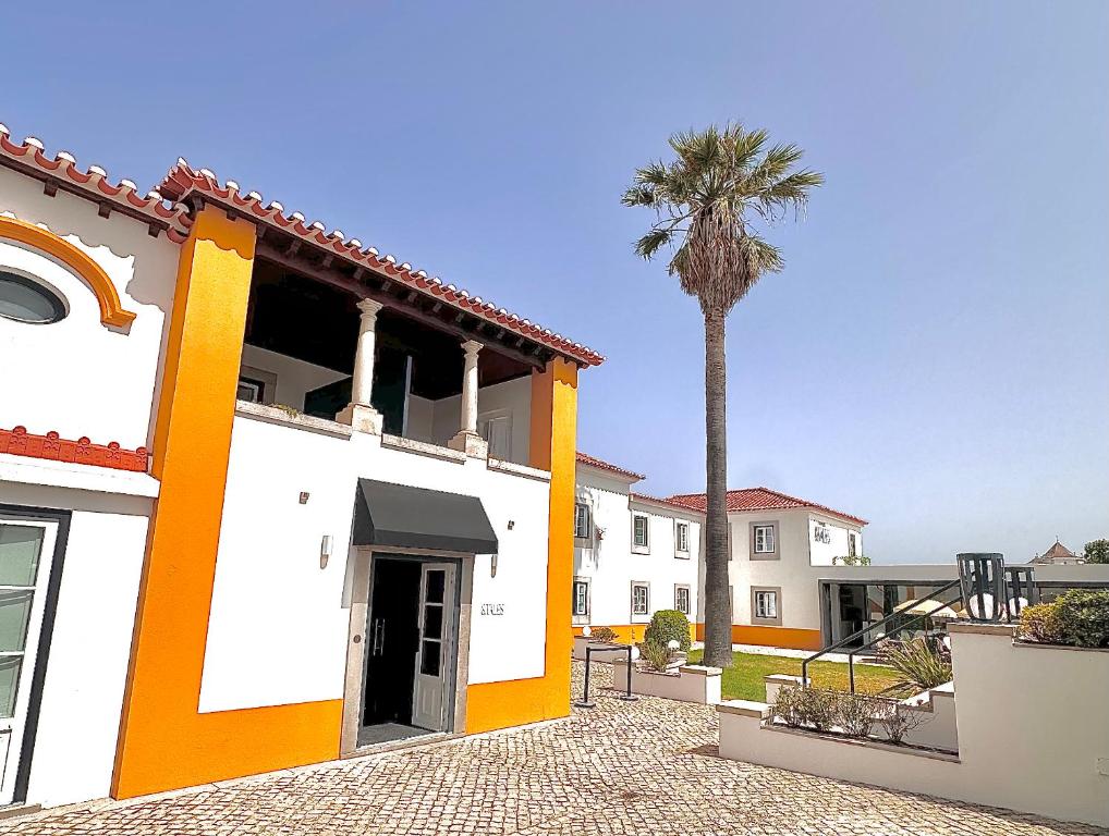 a building with a palm tree in front of it at &Tales Hotel - Óbidos in Óbidos