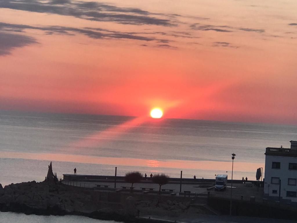 een zonsondergang boven de oceaan met de zon in de lucht bij C'est la vie! in L'Escala