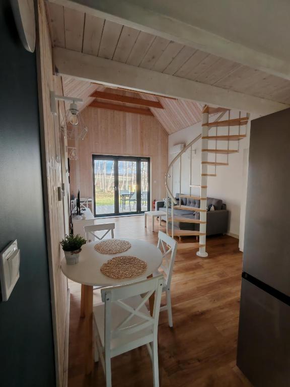 a kitchen and living room with a table and a staircase at Całoroczny domek Morze in Ustka