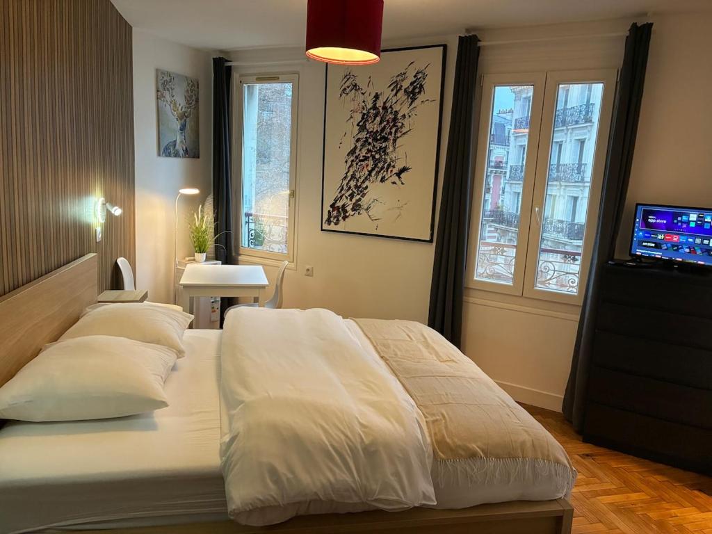 een slaapkamer met een bed met kussens en een televisie bij Studio number 9 in Pantin