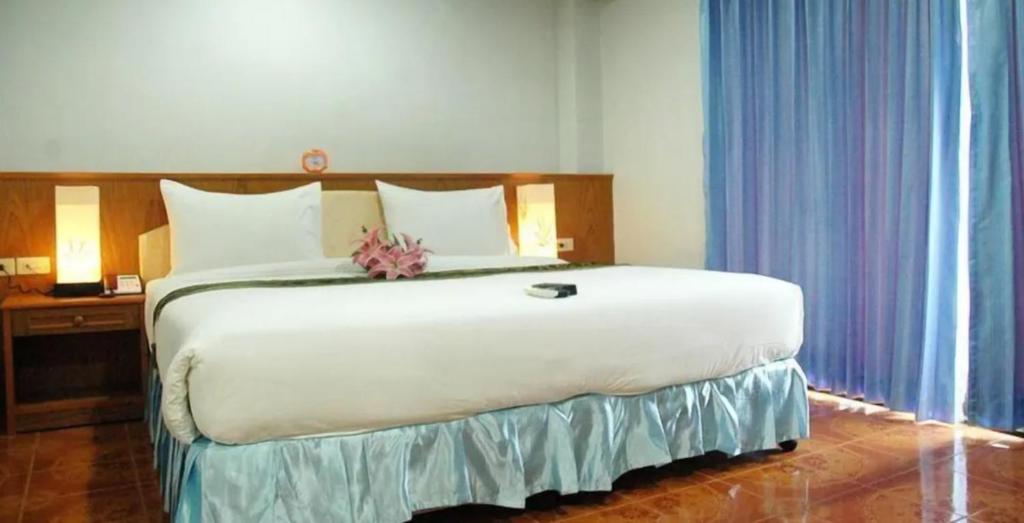 ein Schlafzimmer mit einem großen weißen Bett mit einer Blume darauf in der Unterkunft Patong Lamai Residence in Patong Beach
