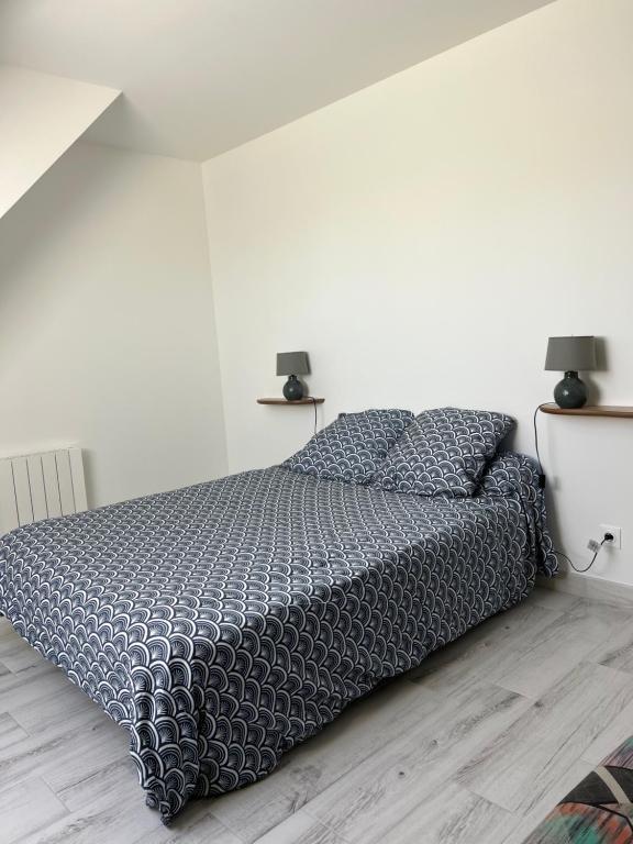 a bedroom with a bed with a black comforter and two lamps at Reinettes in Mulsanne