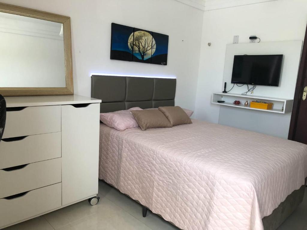 a bedroom with a bed and a dresser and a television at Casa Campos do Mar in Conde