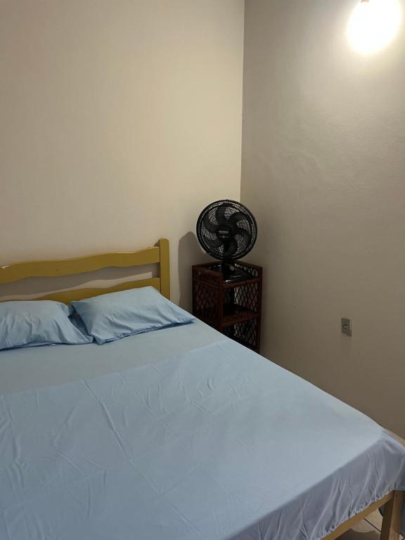 a bedroom with a bed with a blue blanket and a lamp at Pousada Sossego in Pojuca