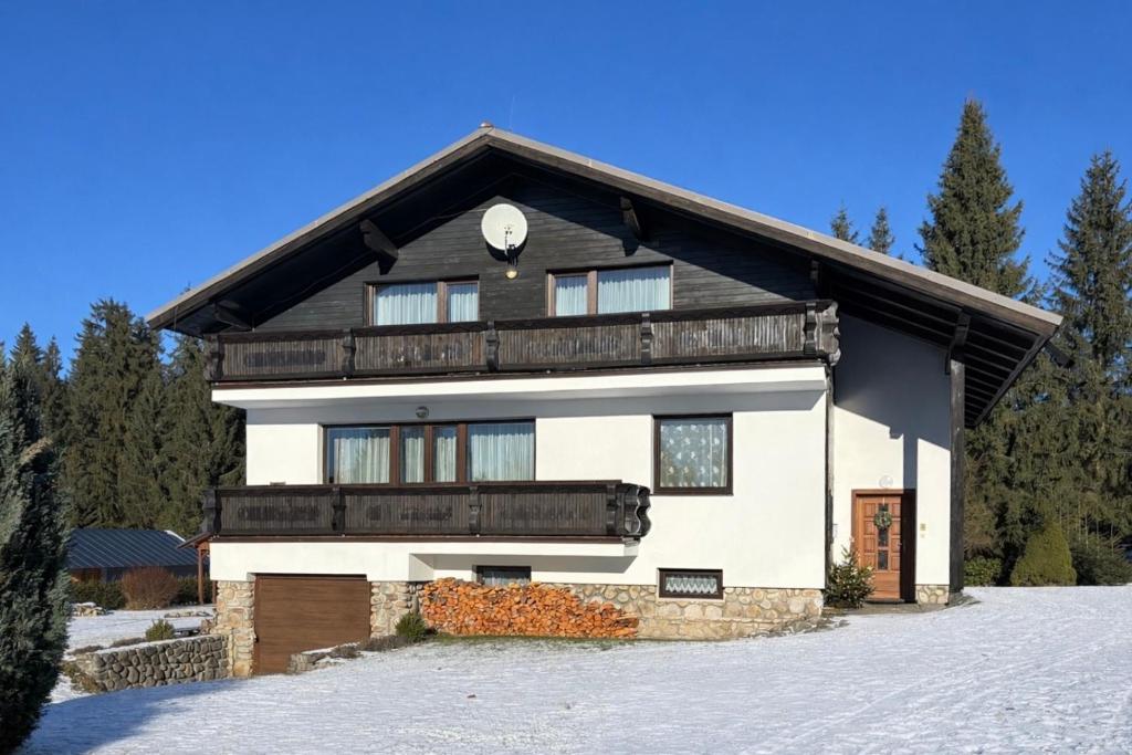 een groot wit huis met een zwart dak bij Pension Burger in Harrachov