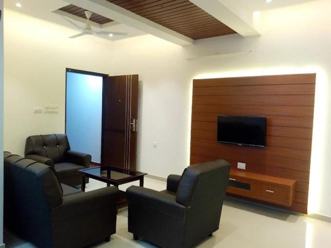 a living room with two chairs and a flat screen tv at Sosh service apartments in Mangalore