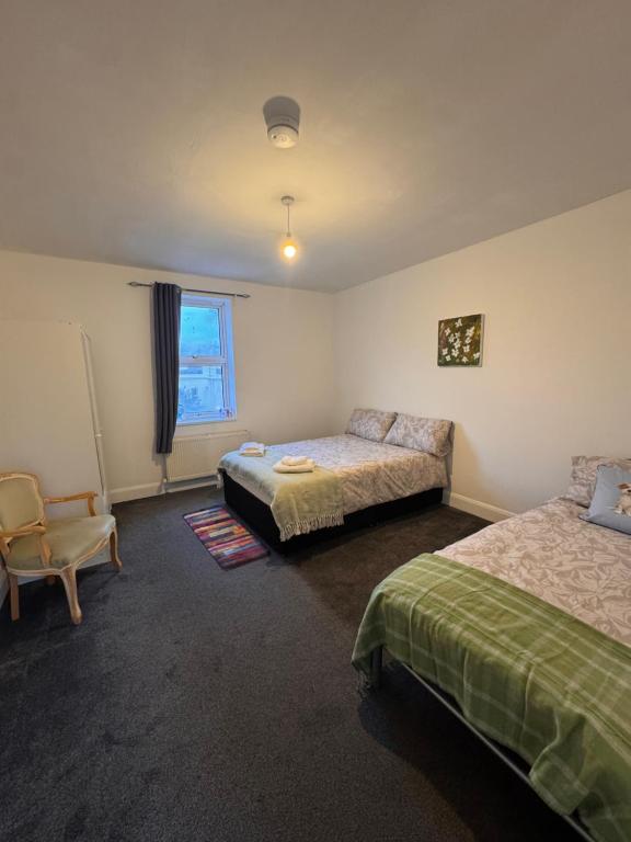 a bedroom with two beds and a chair and a window at NextDoor Morden in Merton