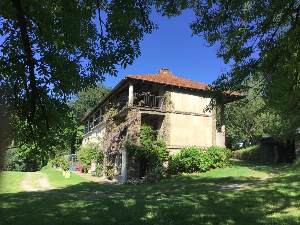 an old building with a balcony on a grass field at La Bouriotte Chambre d'hôtes Bouton D'Or in Labastide-Rouairoux