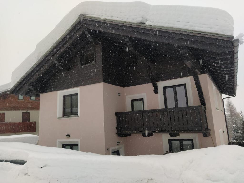 a house with a balcony in the snow at Fiocco di neve in Valdisotto